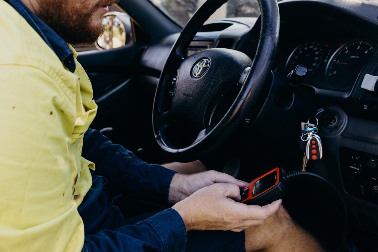 Mechanic using OBD scanner inside vehicle during inspection